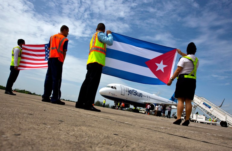 موظفو شركة JetBlue يرفعون الأعلام الكوبية والأمريكية على المدرج بعد استعادة الرحلات الجوية التجارية في عام 2016